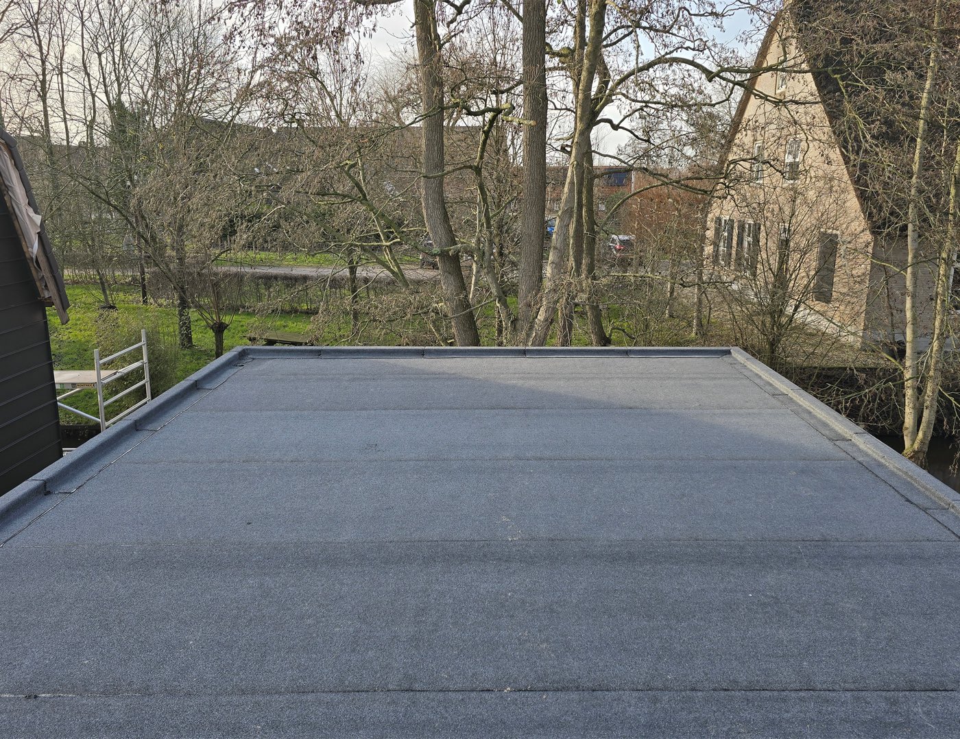 The finished flat roof with new bituminous roofing and an upstand along the edges